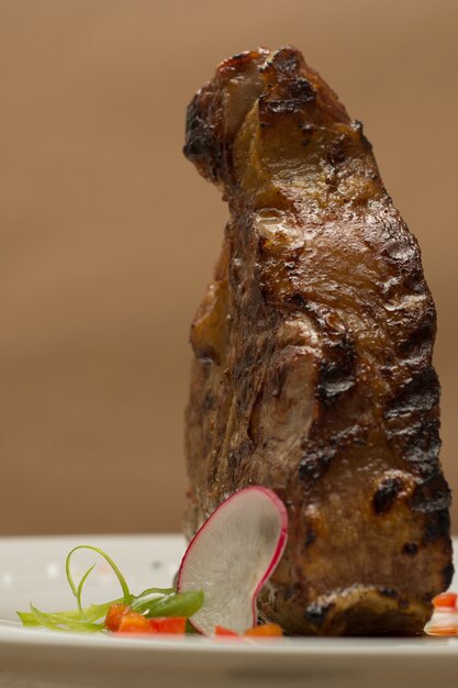 Succulent grilled large t-bone steak garnished with herbs, radish and salt, brown backgrou