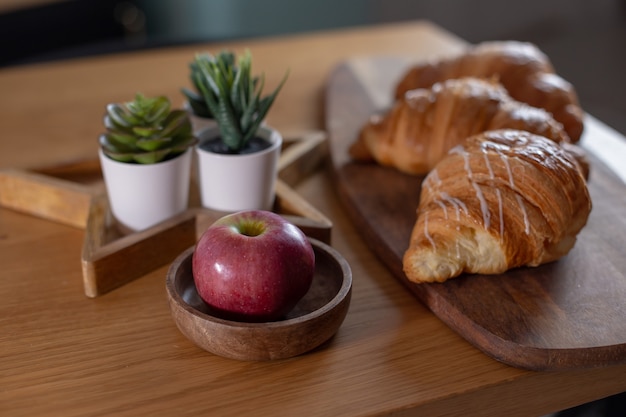 Succulents, croissants, red apple on a wooden table