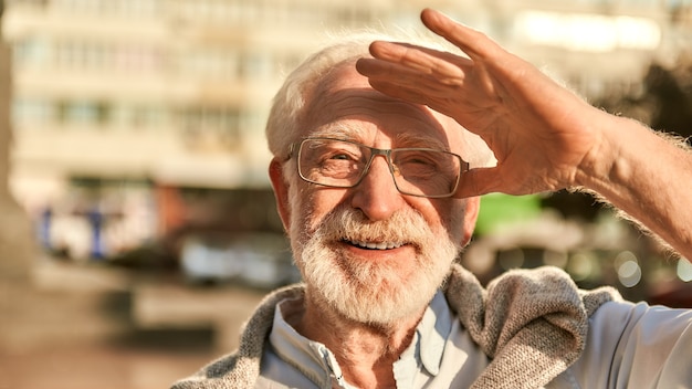 カメラを見て眼鏡をかけた幸せでハンサムなひげを生やした年配の男性のそのような素晴らしい日の肖像画と