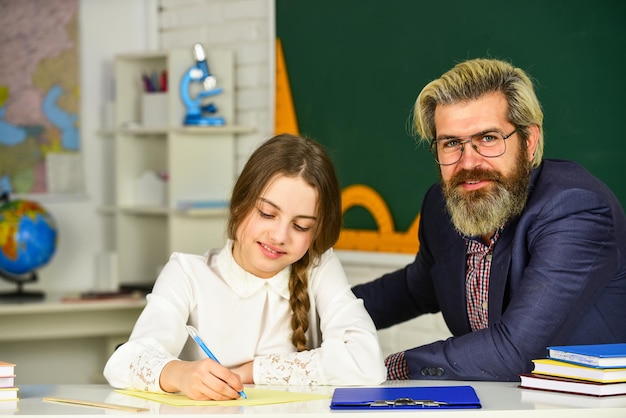 Such an interesting lesson. Little girl and man at blackboard. knowledge day concept. child with teacher in classroom at school. happy teachers day. teacher and schoolgirl on lesson. back to school.