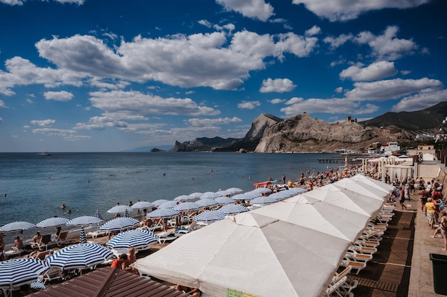SUDAK RUSSIA SEPTEMBER 6 2021 People sunbathe on beach on Black Sea coast on beach in resort town of Sudak in Crimea