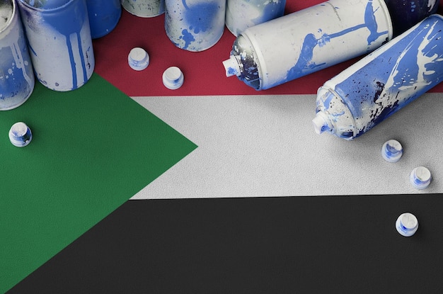 Sudan flag and few used aerosol spray cans for graffiti\
painting street art culture concept