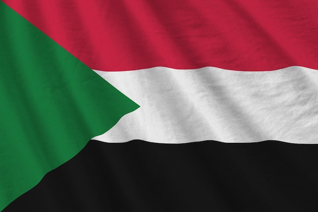 Sudan flag with big folds waving close up under the studio light indoors The official symbols and colors in banner