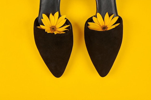 Suede black court shoes with yellow Topinambur flower bud inside toe yellow background womanhood