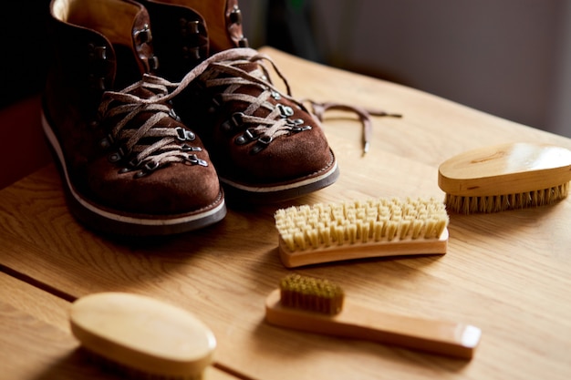 Foto stivali in pelle scamosciata e accessori per la cura sulla tavola di legno