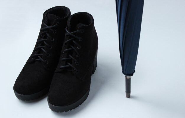 Photo suede boots, umbrella closeup on white table. autumn shoes and accessories