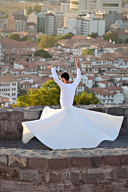Sufi dance at sunset. turkish man performing sufi dance on the\
wall of ankara castle, turkey