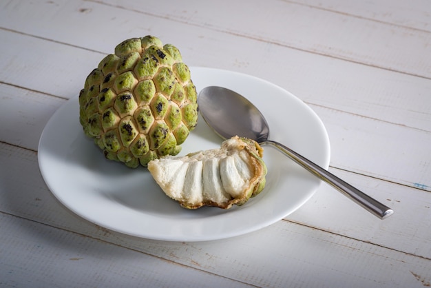 Sugar apple on a white plate with stainless steel spoon ready to be eaten In addition to other sug