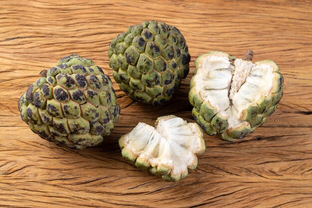 Sugar apples or custard apples with cut fruit over wooden table