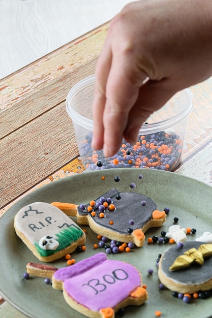 Sugar balls inside a jar. In the blurred foreground, confectioner decorating buttery cookies.