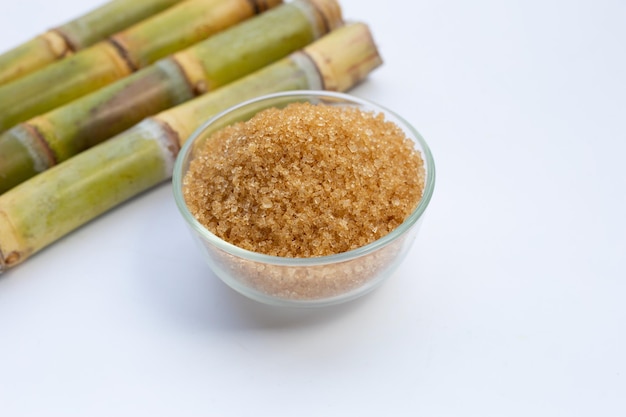 Sugar cane with brown sugar on white background