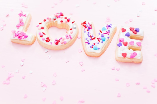 Sugar cookies decorated with royal icing for Valentine's Day  on a pink background.