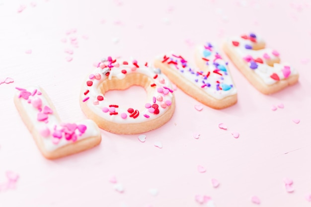 Sugar cookies decorated with royal icing for Valentine's Day  on a pink background.