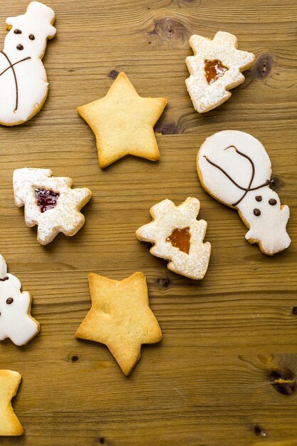 Sugar cookies in shape of snowman, stars, and christmas tree on wood table.