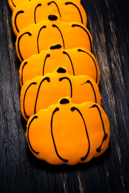 Photo sugar cookies with orange icing shaped like a pumpkin.