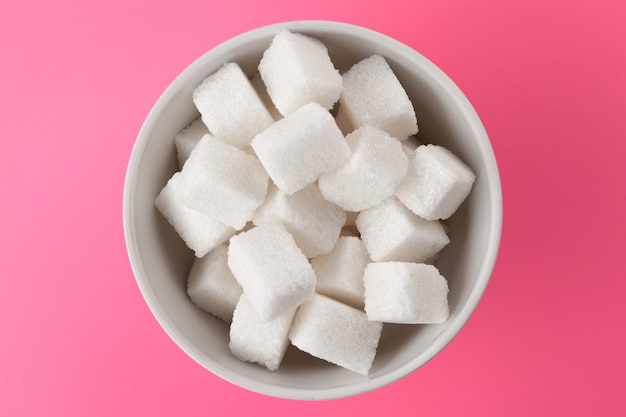 Sugar cubes in a bowl on pink 