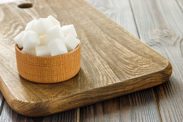 Sugar cubes in bowl on wooden table. White sugar cubes in bowl