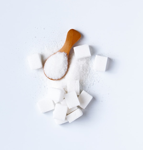 Sugar cubes and sugar in spoon. White sugar on white background. Different sugar