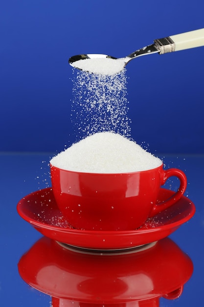 Sugar in cup on blue background