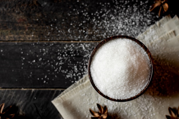 Sugar in a cup and spoon on a black table.