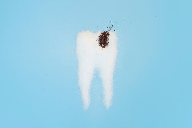 Sugar destroys tooth enamel and leads to tooth decay. Sugar are laid out in the form of tooth and coffee symbolizes caries.