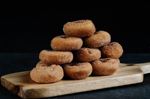 Photo sugar donuts on wooden board with black background