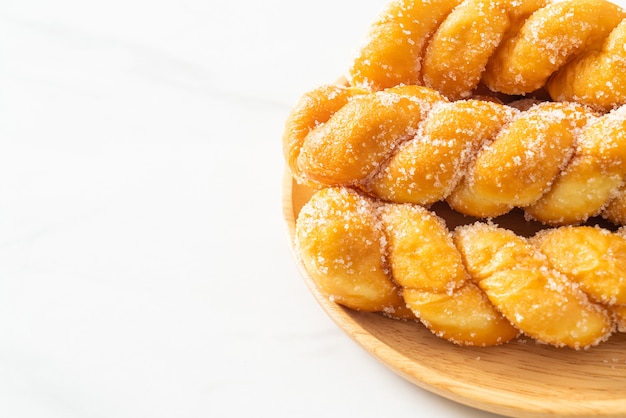 sugar doughnut in spiral shape on wooden plate