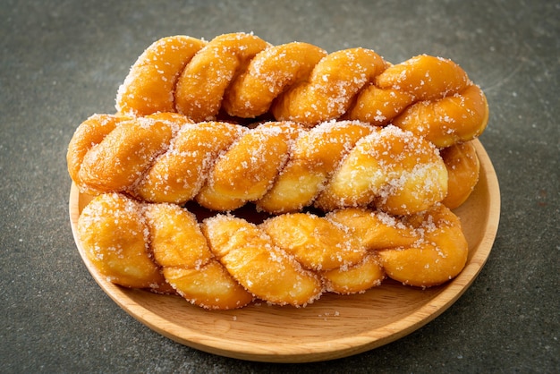 Sugar doughnut in spiral shape on wooden plate