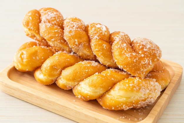 sugar doughnut in spiral shape on wooden plate