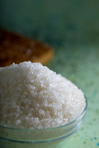 Sugar in glass bowl on wooden background