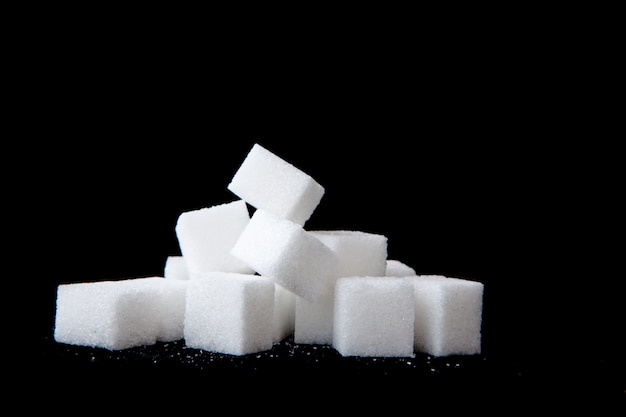Photo sugar lumps piled up together against a black background