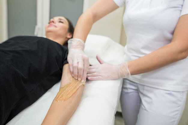 Sugar paste hair removal procedure shugaring Cosmetologist applies sugar paste to the hand of a young womanDepilation of female hands in a beauty parlor