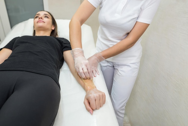 Sugar paste hair removal procedure shugaring Cosmetologist applies sugar paste to the hand of a young womanDepilation of female hands in a beauty parlor