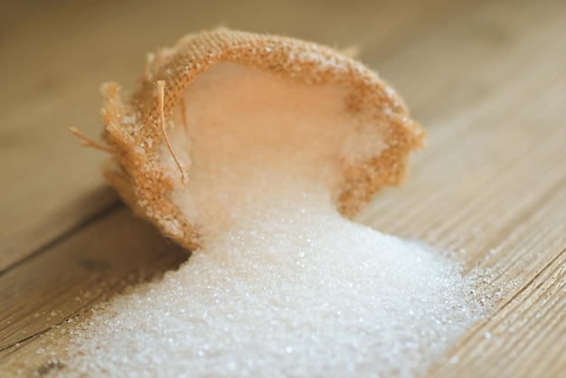 Foto zucchero su sacco e fondo in legno zucchero bianco per alimenti e dolci caramella da dessert mucchio di granulato cristallino di zucchero dolce