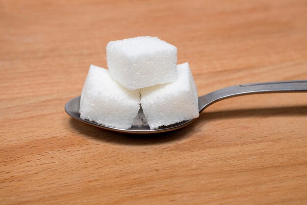 Sugar on a spoon on a wooden natural