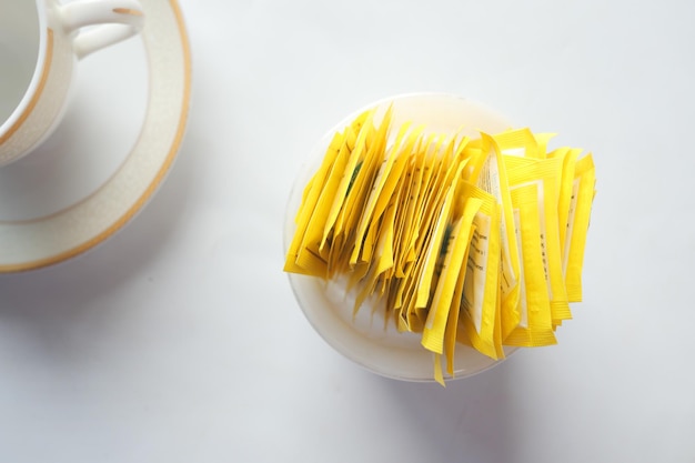 Sugar substitute sweetener packet and tea cup on white\
background