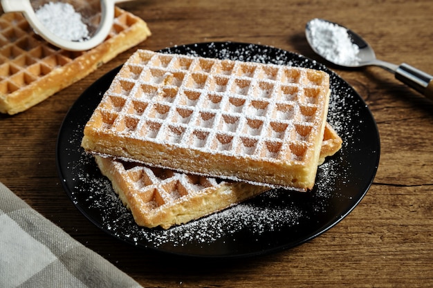 Sugar waffles presented on a black plate