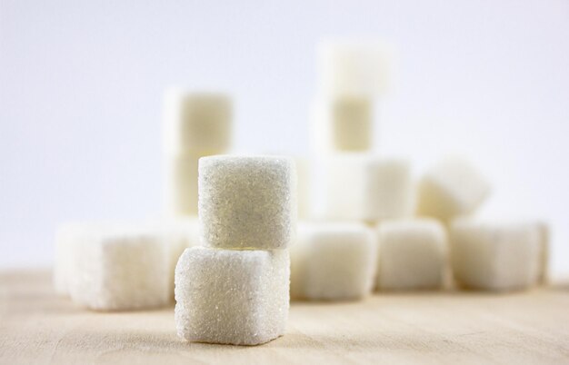 Sugar on a wooden saucer Wooden plate with sugar cubes on a white background