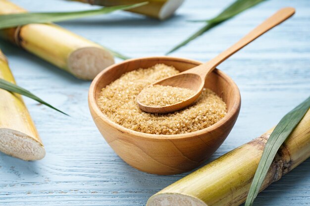 Sugarcane and brown sugar on a wooden background closeup