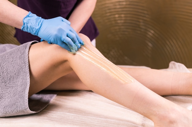 Sugaring epilation skin care with liquid sugar at legs. You can see her smooth and hair free legs