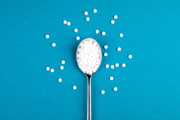Фото Сахарозаменяющие таблетки с ложкой на синем фоне