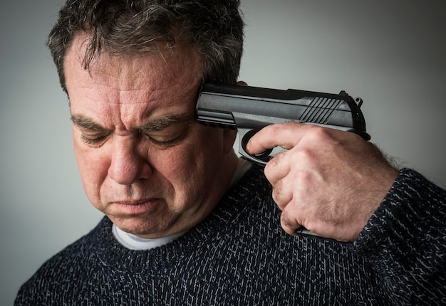 Foto uomo suicida con una pistola alla sua tempia.