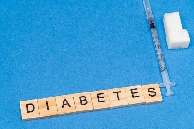 Suiker, spuit en woord diabetes op blauwe achtergrond