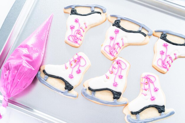 Foto suikerkoekjes in de vorm van kunstschaatsen versieren met royal icing.