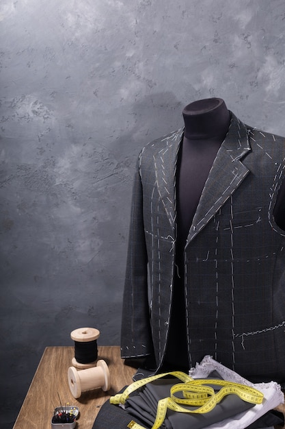 Suit jacket on male tailor mannequin and sewing tools, creative concept of clothes atelier