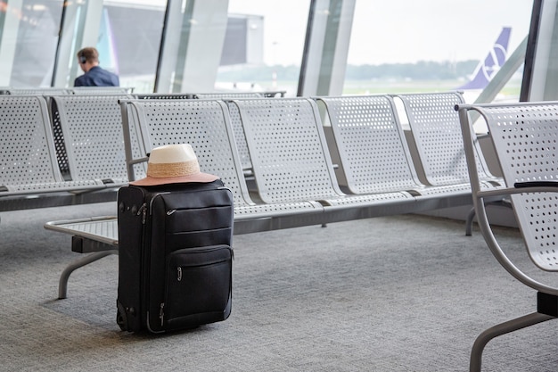 空港の待合室にあるスーツケース、空港の待合室にある1つの黒いスーツケース。