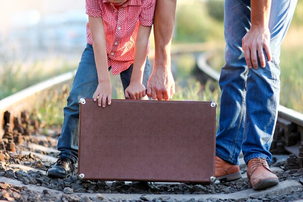 Suitcase father and son hold suitcase near the railroad