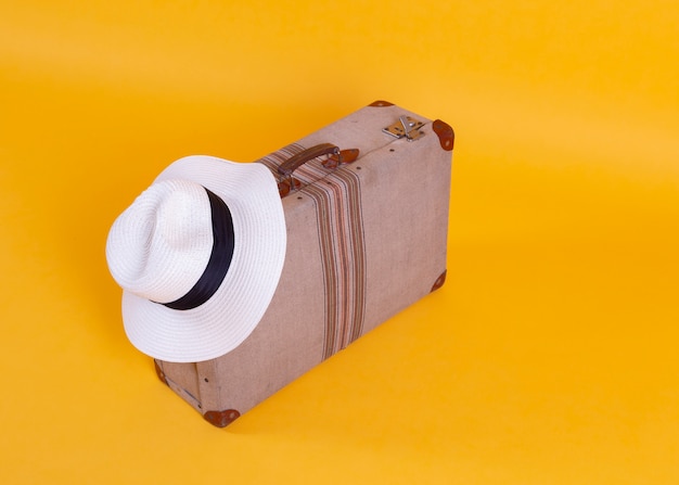 Foto cappello della macchina fotografica della foto della valigia, fondo giallo, concetto di viaggio