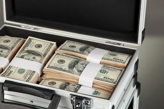 suitcase with 100 dollar bills on grey background
