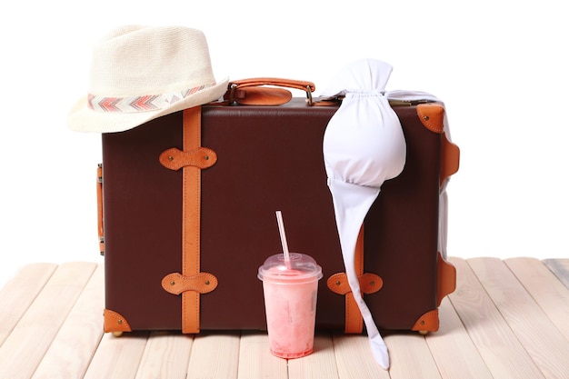 Photo suitcase with beach accessories on wooden board on white background